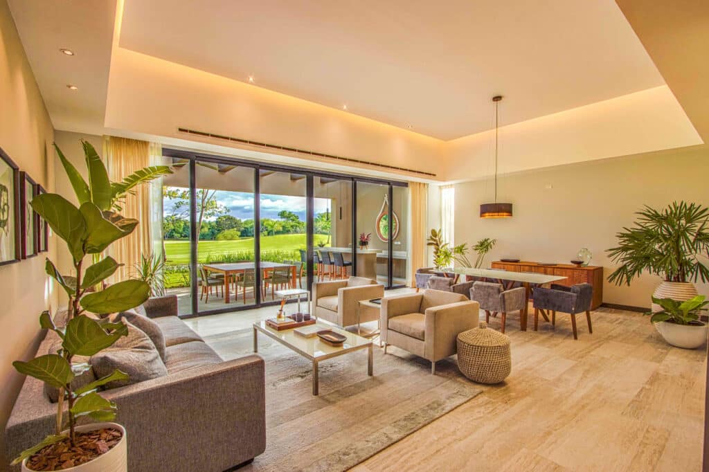 Living room at Amanha A-16 in Yucatan Country Club, Merida, featuring a spacious seating area with large sliding glass doors opening to a green outdoor space.