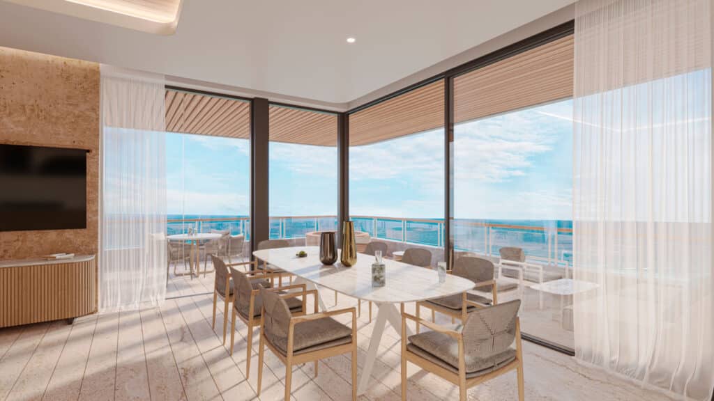 Interior view of BAO B-803, a beachfront condo in Puerto Morelos, featuring a dining area with large windows overlooking the ocean and a balcony outside.