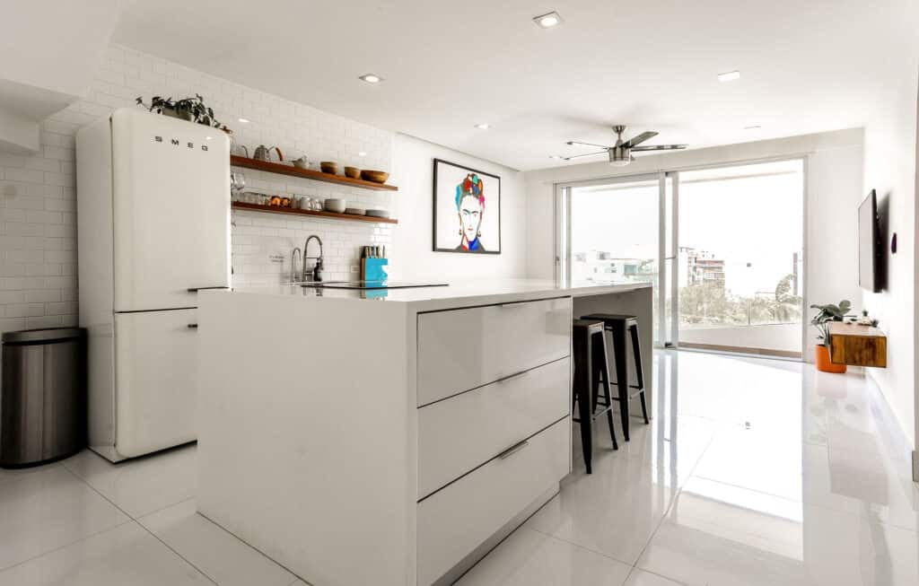 Modern white kitchen in DK05 – 401 penthouse, Playa del Carmen, with open layout, minimal decor, and large windows overlooking the city.