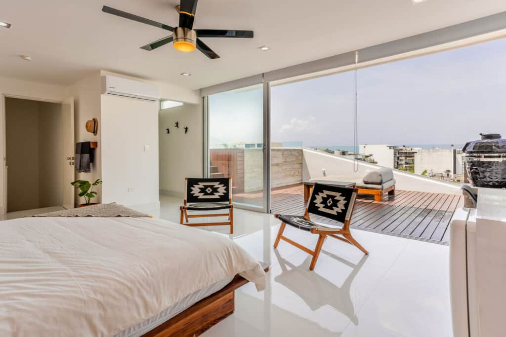 Bright beachfront penthouse in DK05 – 401 with large glass doors opening to a terrace and ocean views, modern decor, white floors, ceiling fan, and outdoor lounge., Playa del.