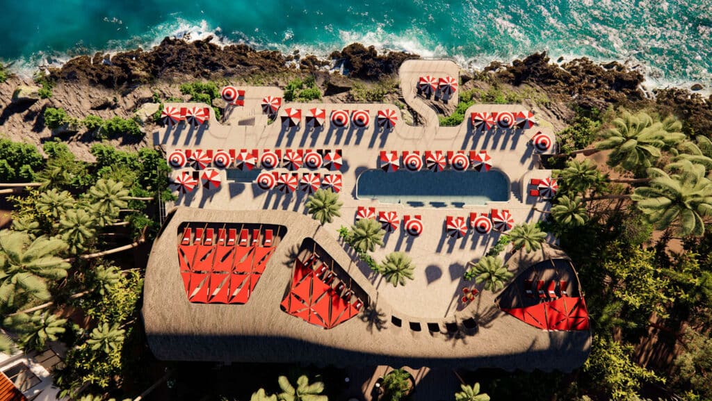 An aerial view of Faena District B in Tulum showing a rocky coastline, swimming pool, sun loungers, and red-and-white umbrellas among lush palm trees.
