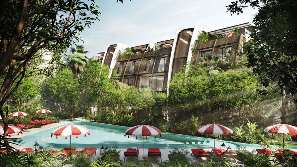 An outdoor pool area surrounded by lush greenery with modern residential buildings of Faena District B in Tulum in the background.