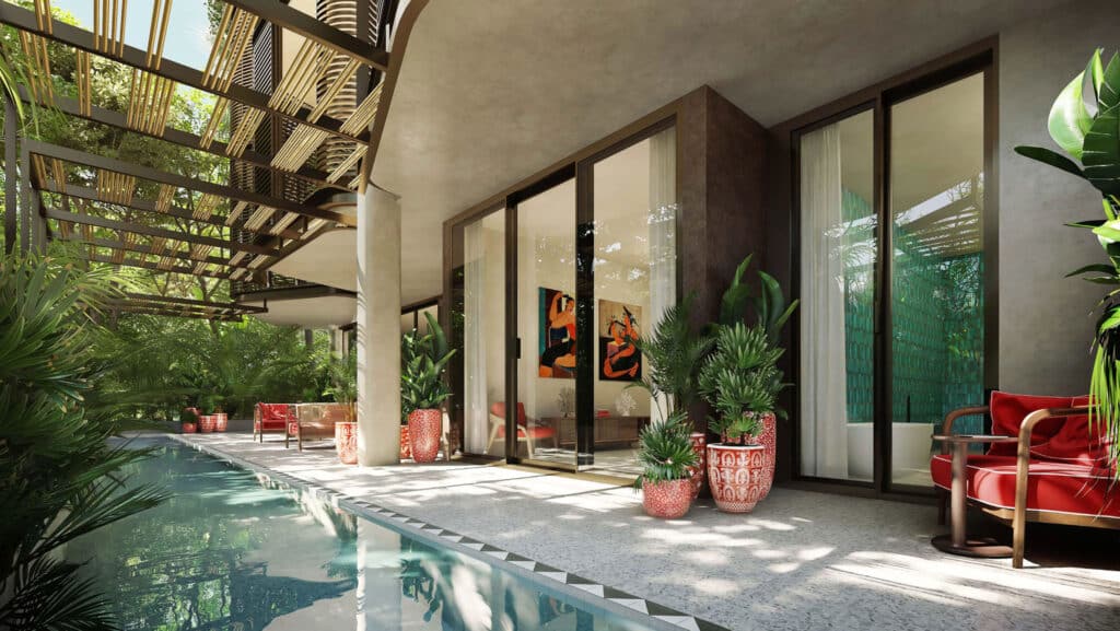 Indoor pool area at Faena District B in Tulum featuring large glass doors, vibrant red seating, and lush green plants creating a luxurious and tranquil atmosphere.