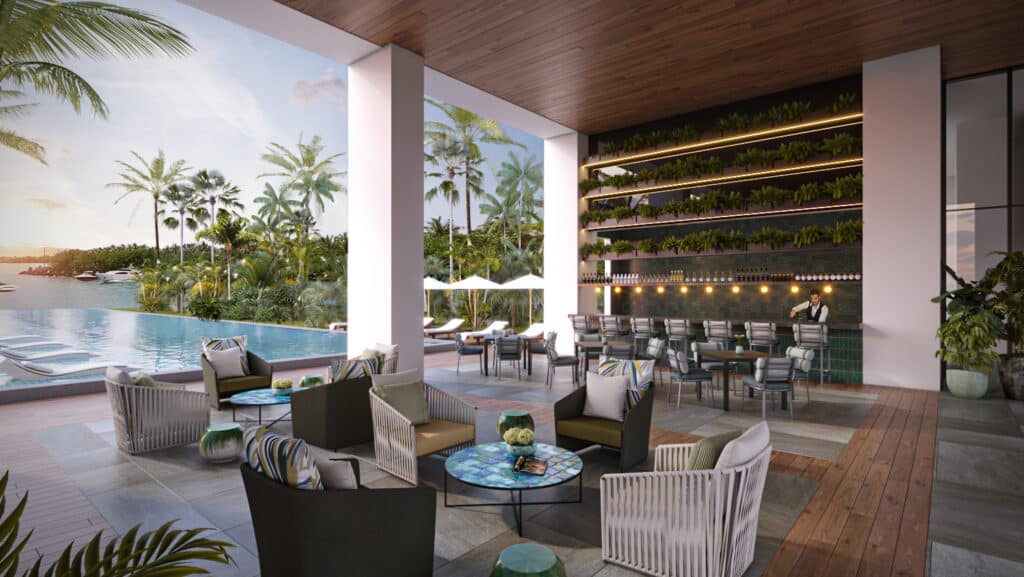 Interior view of SLS Bahia Beach 1403 in Cancun, showing a lounge area with chairs and tables, overlooking a pool and lush tropical landscaping in the Marina Front development.
