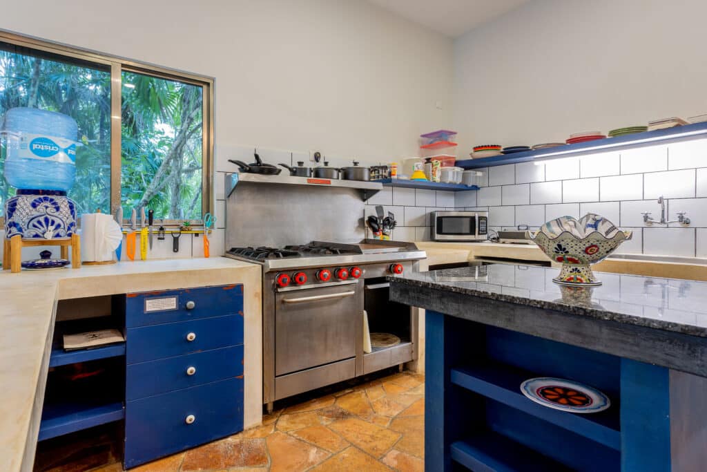 Kitchen area in Autumns Retreats, Tankah Bay, Tulum, featuring a gas stove, microwave, and colorful ceramic accents.
