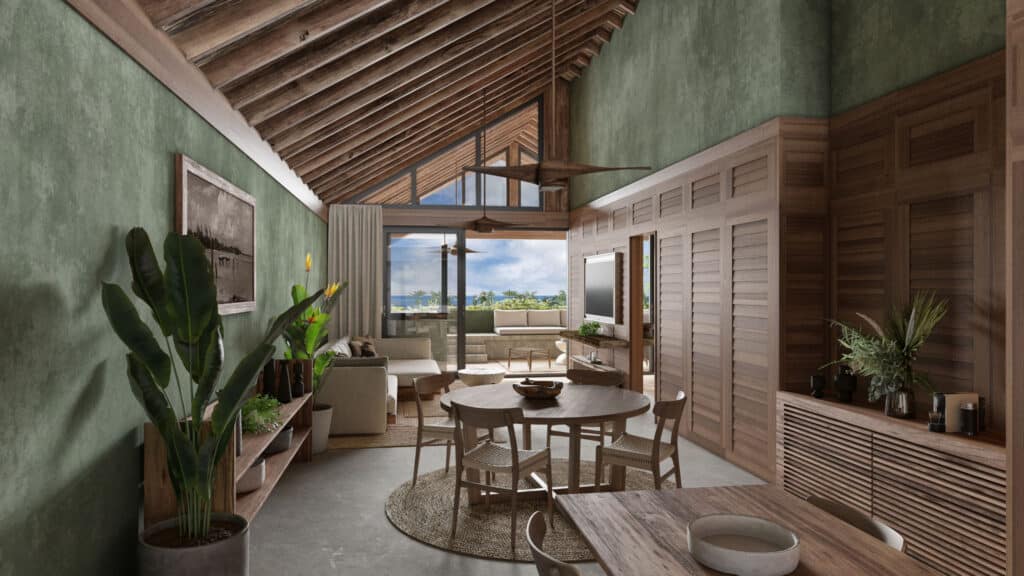 Interior view of a beachfront residence at Acalai 303 in Tulum, featuring wooden ceiling, a green accent wall, a round dining table, and a living area with a view of the outdoors.