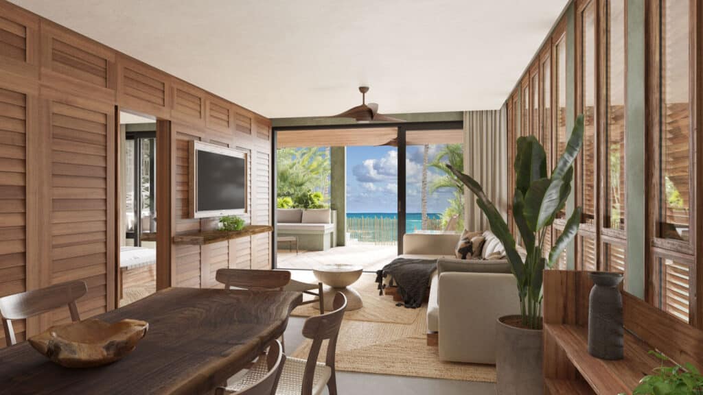 The interior of Acalai 303 beachfront residence in Tulum features wood paneling, a cozy living area with tropical decor, and access to a balcony with ocean views.