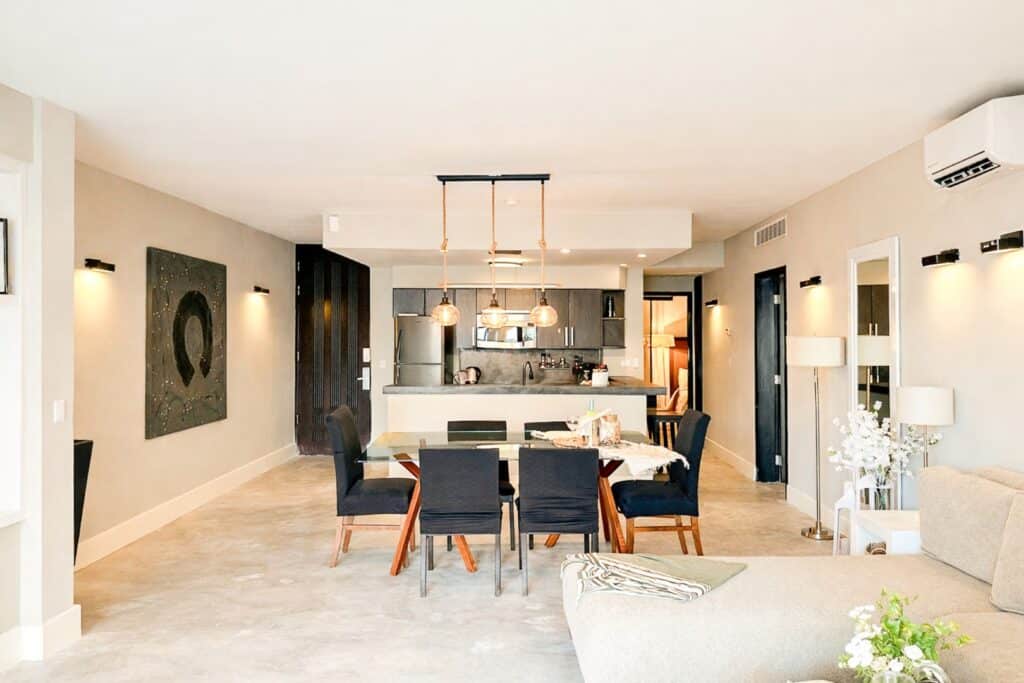 Interior of a modern living space with open kitchen, dining area, and minimalist decor at Aldea Thai in Playa del Carmen.