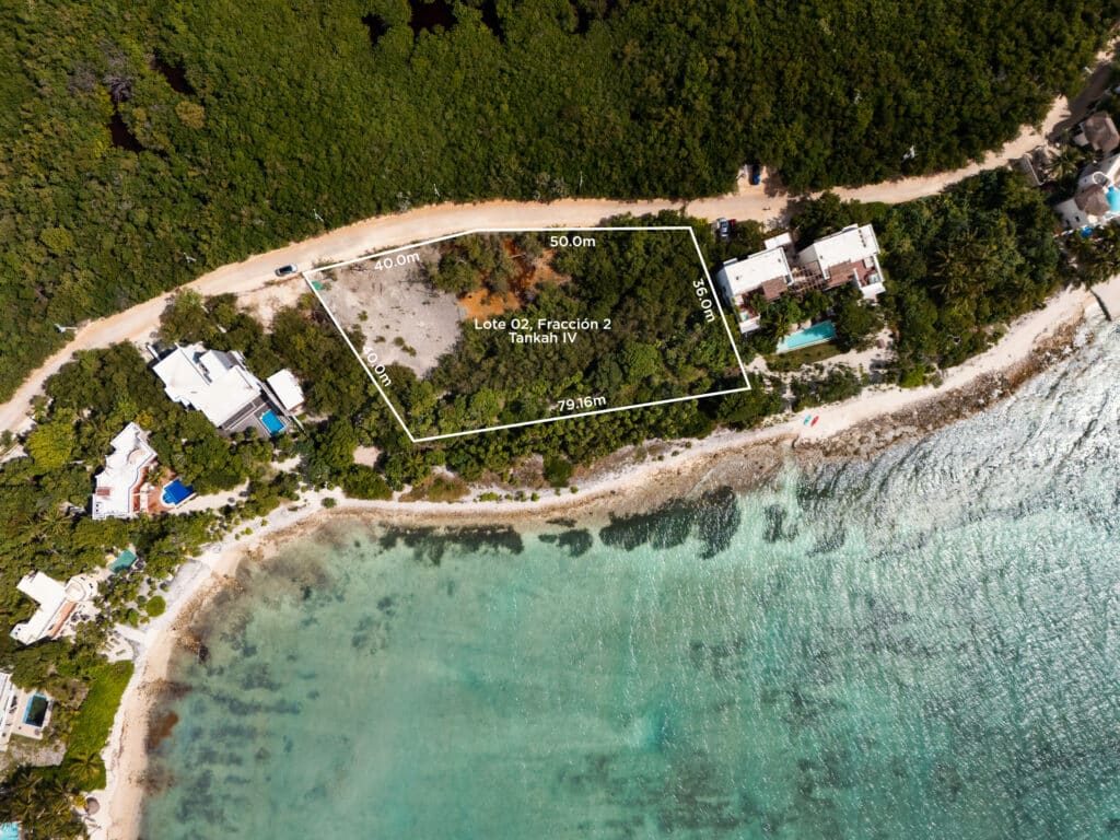 Aerial view of a beachfront land lot in Tankah Bay Beachfront Land in Tulum, showing the plot outlined with measurements along the beach and forest, next to nearby houses and the shoreline.