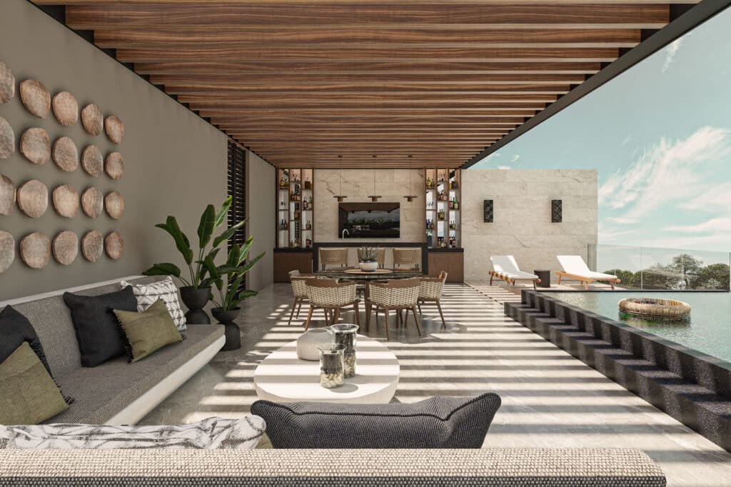 A spacious outdoor lounge with a sofa, armchairs, and potted plants overlooks a swimming pool with lounge chairs and a view of trees and blue sky in Merida's Hacienda Xcanatun area.