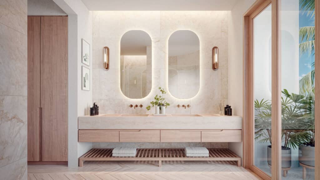 Modern bathroom with large oval mirrors, wooden accents, and sliding glass doors opening to a balcony with lush greenery in Marina Front, Puerto Aventuras.