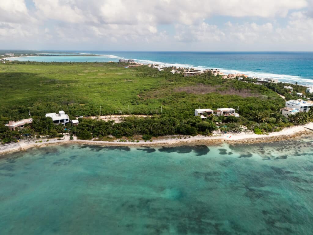 Aerial view of Tankah Bay Beachfront Land in Tulum, showing lush greenery, beachfront properties, and turquoise waters along the coast.