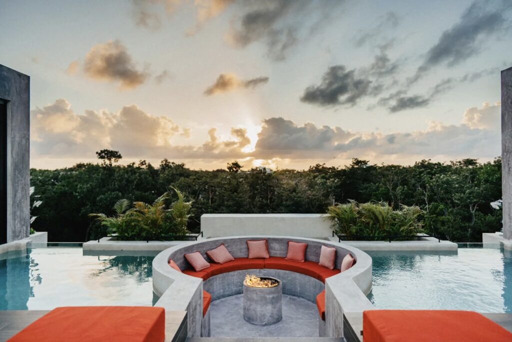 A luxurious rooftop swimming pool at Casa Don Rey in Aldea Zama, Tulum, offering a relaxing space with views of the surrounding forest during sunset.