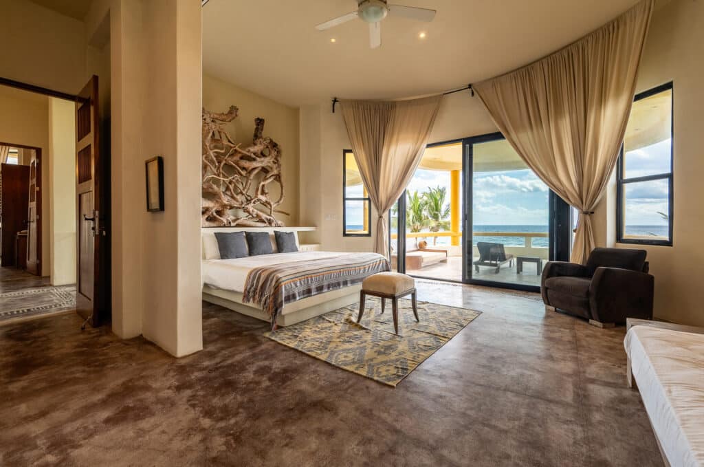 Interior view of Espirit del Mar Ocean Front House 4 in Punta Sur 5, Akumal, featuring a bedroom with a balcony overlooking the beach and ocean.