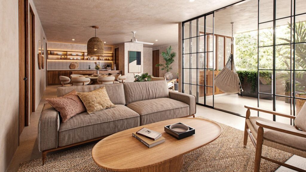 Living room with a beige sofa, wooden furniture, and large glass doors opening to a balcony with greenery in Santa Ana, Merida, at Qanaai Nah 101.