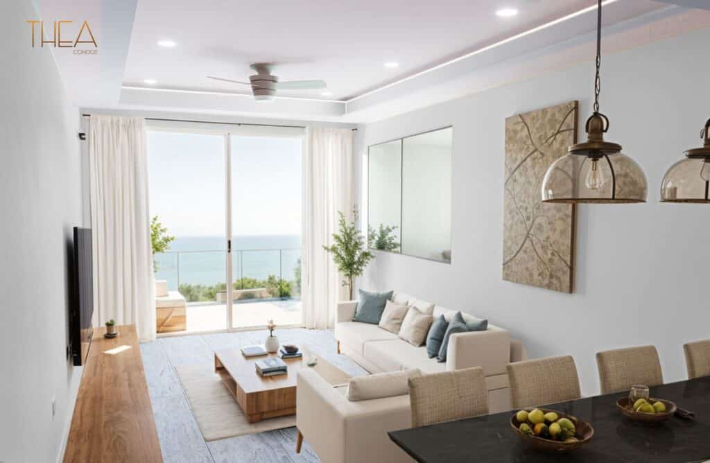 A bright living room in Thea 502 condos in Puerto Morelos features white walls, a large sliding door with a balcony view of the ocean, and modern decor with a neutral color palette.