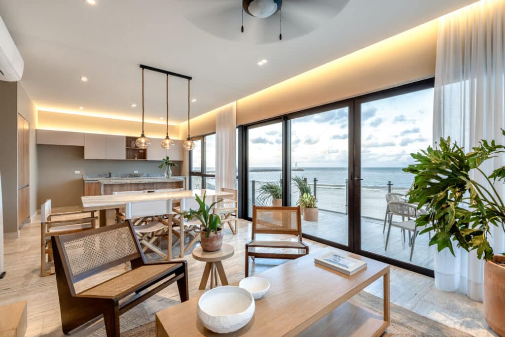Interior view of Bonanza PH in Progreso's Marina Front area, showcasing a modern living space with large windows overlooking the beach and ocean, with stylish furniture and decor.