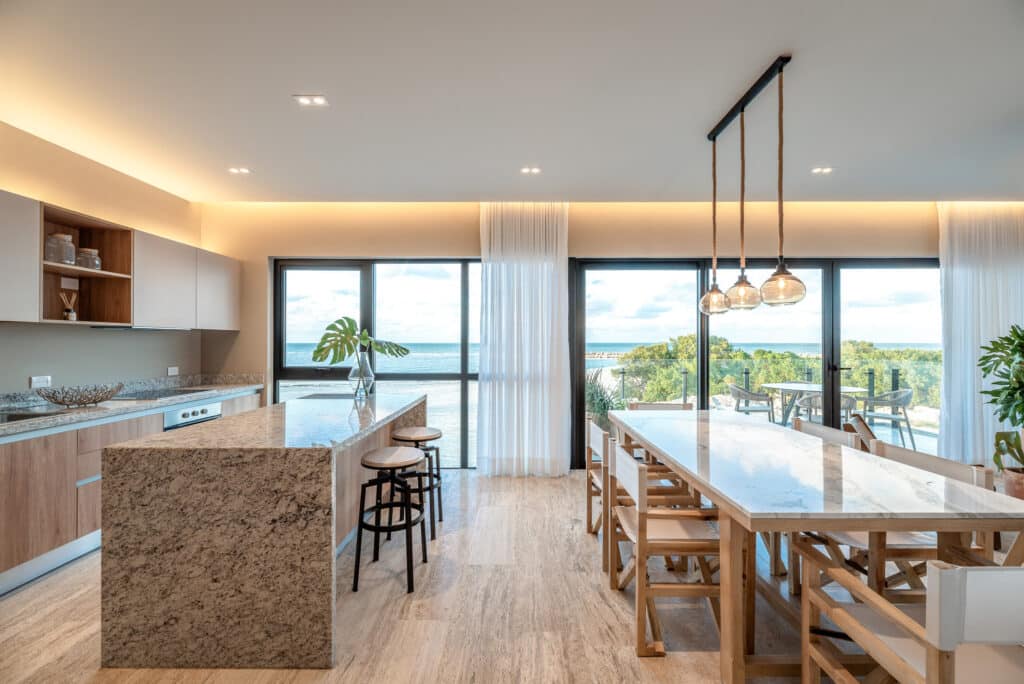 Interior view of Bonanza PH-1214 in Progreso's Marina Front area, featuring a modern kitchen with granite countertops and a spacious dining area with large windows overlooking the ocean.