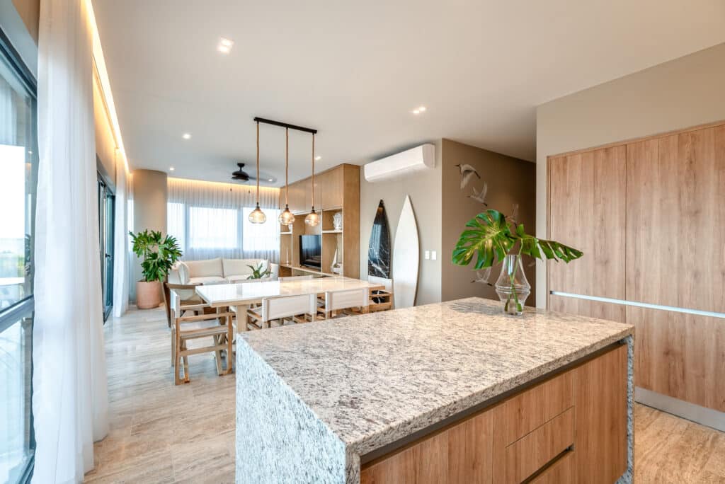 Interior view of a modern, open-concept living and dining area in Bonanza PH, Progreso, featuring a kitchen with a granite island, wooden accents, and natural light.