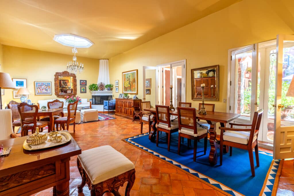 Interior of Casa Carolina in San Miguel de Allende's Centro Histórico featuring colorful artwork, a fireplace, and classic wooden furniture with vibrant decor accents.