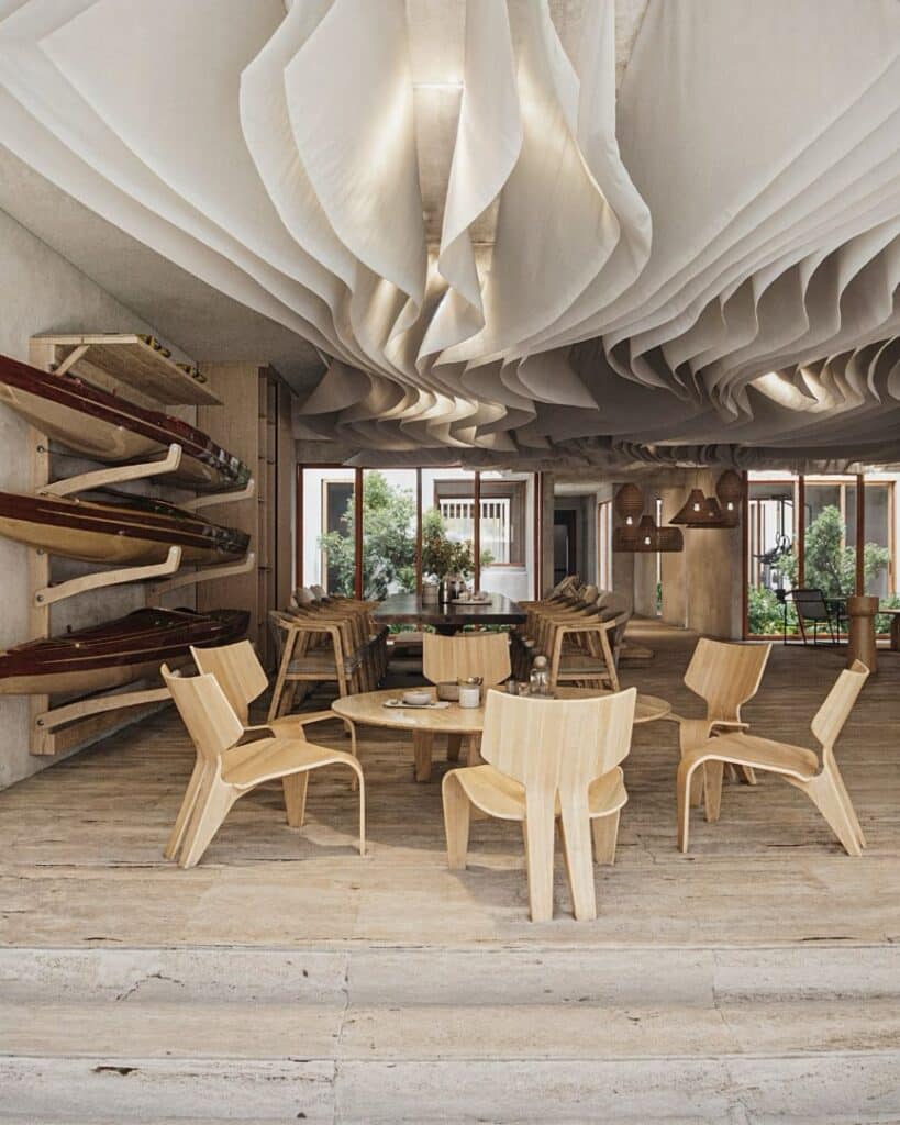 Interior of Maranta 203 Beachfront condos in Tulum featuring a spacious dining area with wooden chairs, large windows, and a decorative ceiling sculpture.