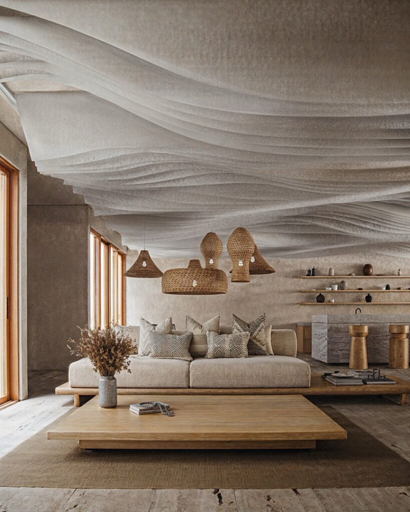 A living room at Maranta 203 Beachfront in Tulum features a neutral-toned sofa with patterned cushions, wooden accents, woven pendant lights, and a textured ceiling.