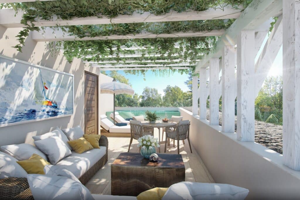 A cozy outdoor terrace at Puerta Azul Tulum 101 in Aldea Zama, Tulum, featuring a seating area, a small pool, and lush greenery overhead.