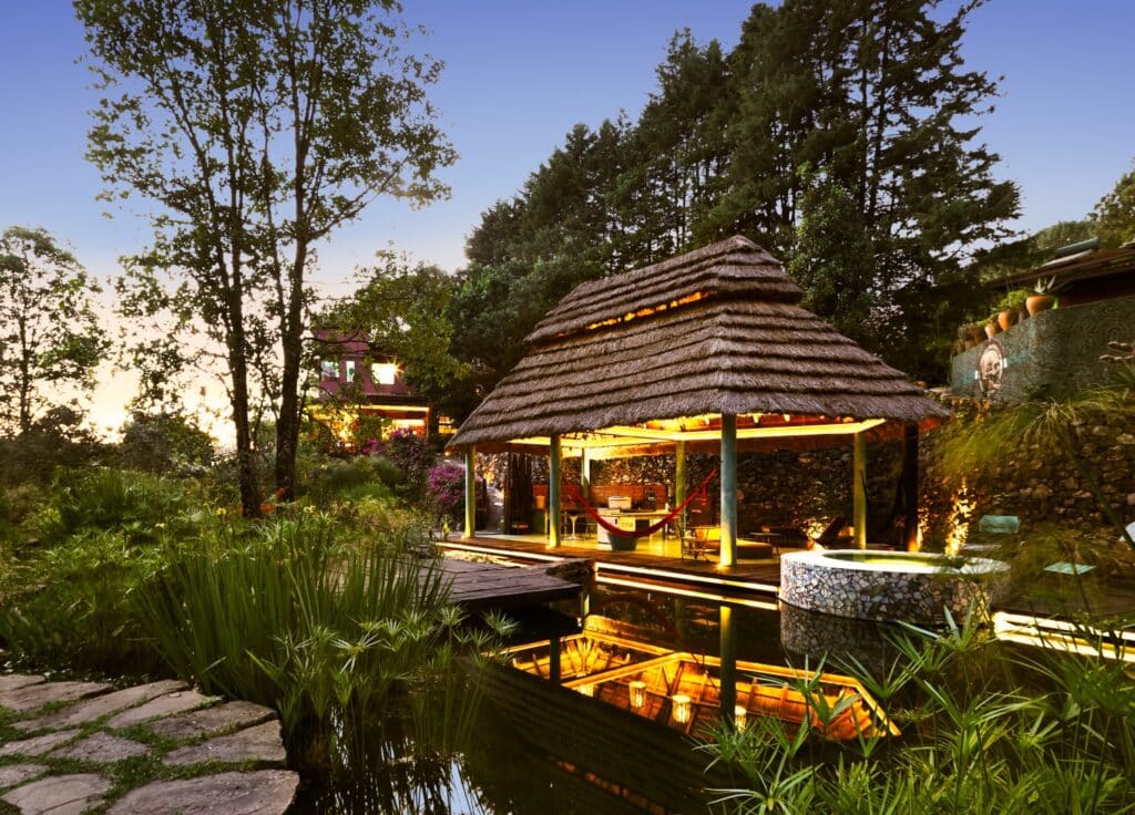 A cozy open-air pavilion with a thatched roof is surrounded by lush greenery and trees in Cerro Colorado, Loma De Rodriguez, at Ah0 Art Villa & land.