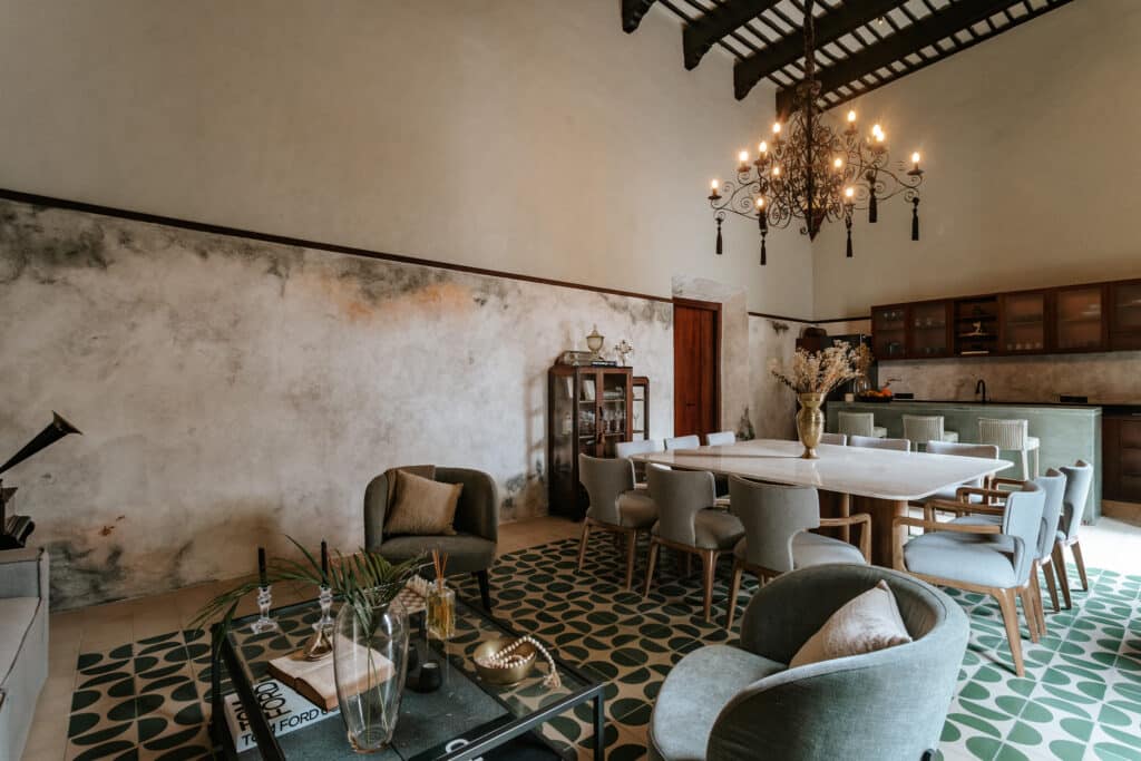 Interior view of CASA AXIOTIC MERIDA VILLA 2 in Merida, featuring a spacious dining area with a chandelier, a mix of modern and rustic decor, and patterned green and white tile flooring.