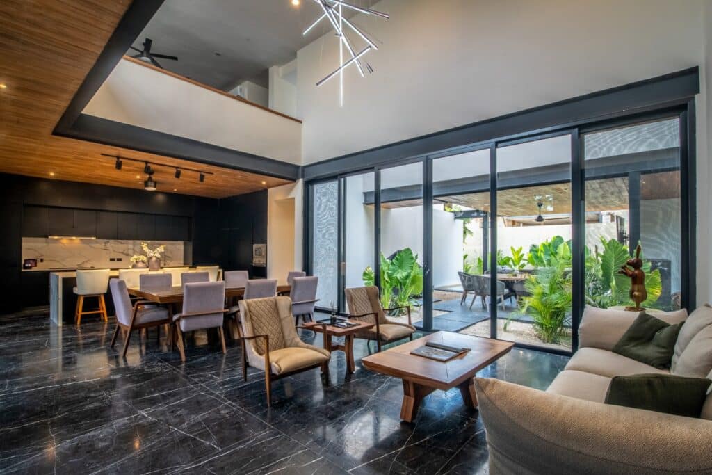 Interior of Casa Orion Villa 2 in Compostela Orion 61, Merida, featuring a modern living room with black marble floors, large glass doors opening to a garden space.