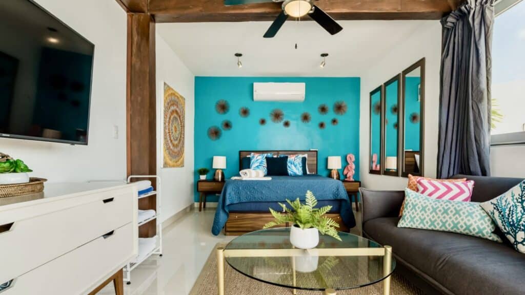 Interior view of the Oasis Penthouse in Playa del Carmen's Centro area, featuring a bedroom with blue accent wall, decorative wall art, and modern furnishings.