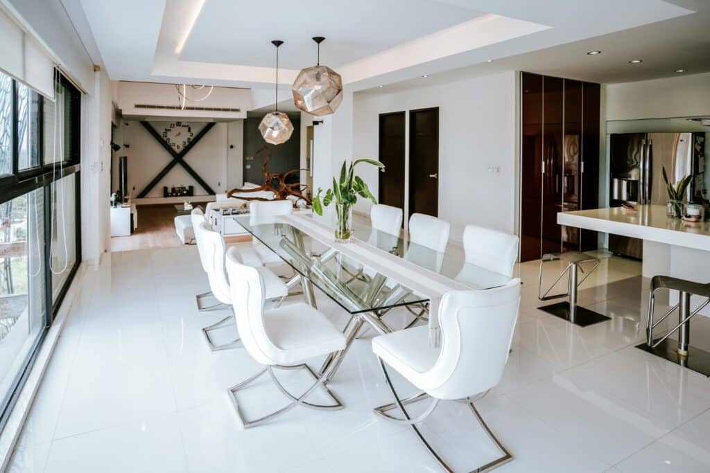 Interior view of Torre Onze Penthouse 3 in San Gertrudis Copo, Mérida, showing a spacious dining area with white chairs around a glass table, modern lighting, and open living.