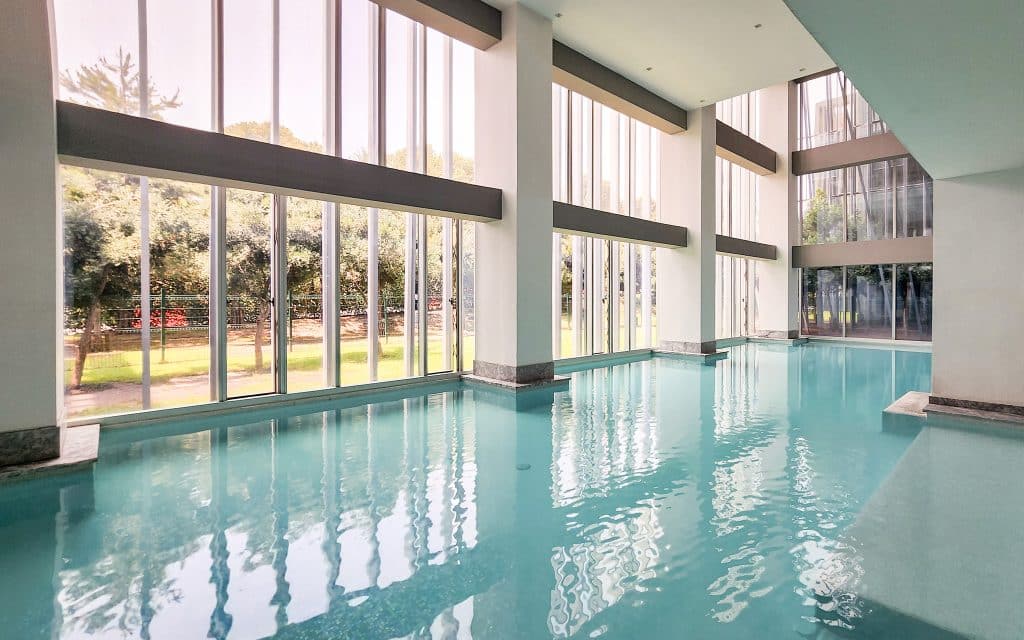 Interior view of Paradox 24 A in Santa Fe, Mexico City, featuring a spacious swimming pool with large floor-to-ceiling windows allowing natural light to fill the space.