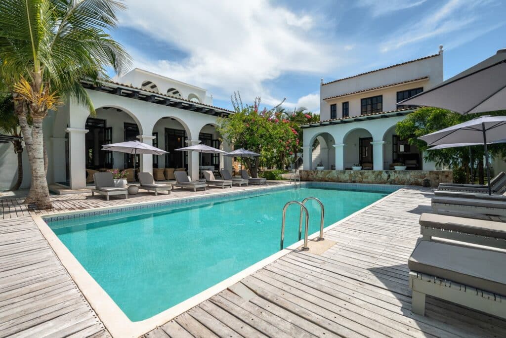 Rae’s Villa in Tulum with a pool, surrounded by palm trees and white buildings in Region 8
