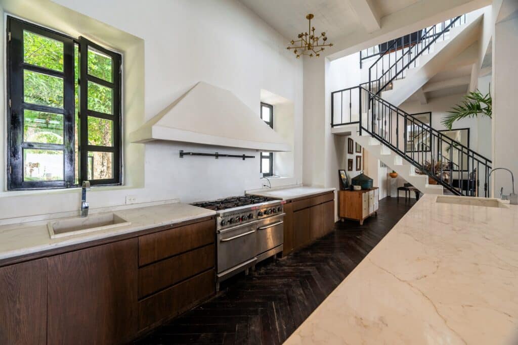 Interior of Rae’s Villa in Tulum, featuring a kitchen with dark wooden cabinets, a large marble countertop, black window