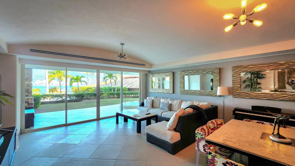 Beachfront condo at Villa Alejandra Garden 1000 in Acapulco, with living area, sliding glass doors to patio, tropical view