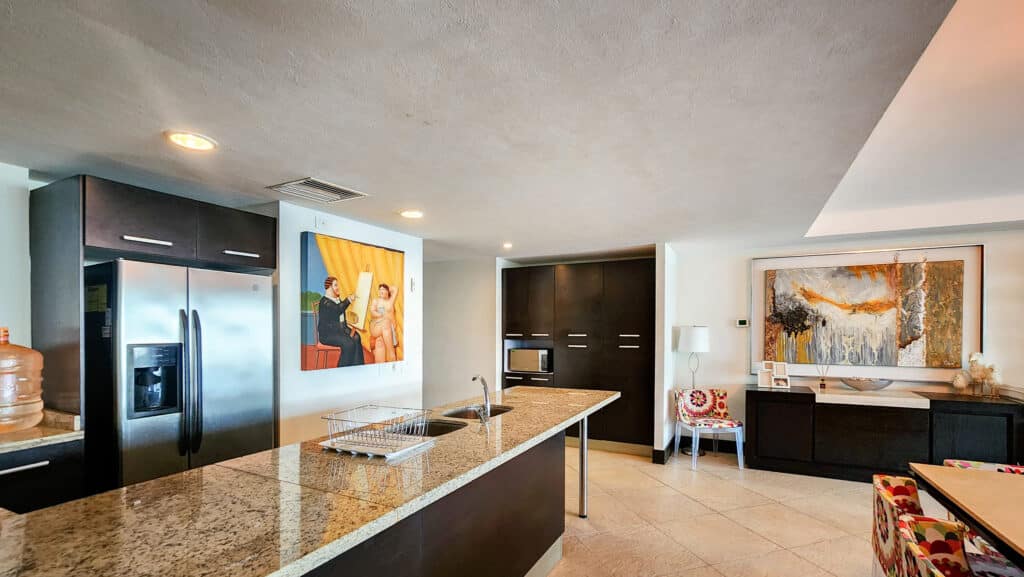 Interior view of a beachfront condo at Villa Alejandra Garden 1000 in Acapulco, showcasing a kitchen with dark cabinets and