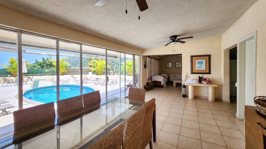 Interior view of Lomas Del Marques House in Acapulco with a dining area, sliding glass doors, and a backyard pool area