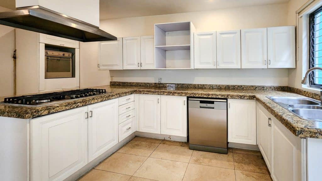 Kitchen in a Milton 64 home in Miguel Hidalgo, Mexico City, featuring white cabinetry, granite countertops, and stainless steel appliances.