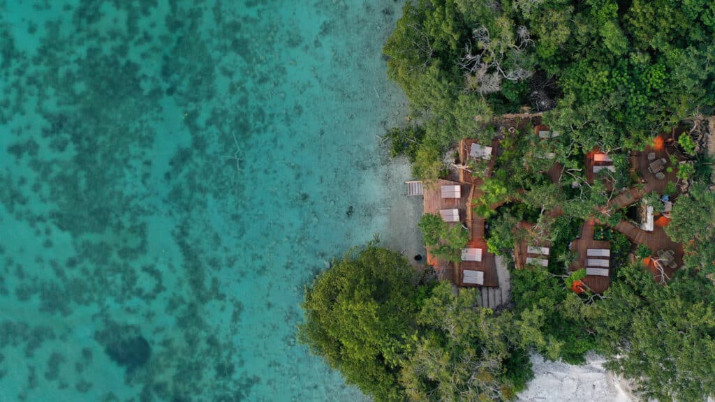 Aerial view of the 13-Room Lake Front Bacalar Hotel surrounded by lush greenery and wooden decks overlooking turquoise lake