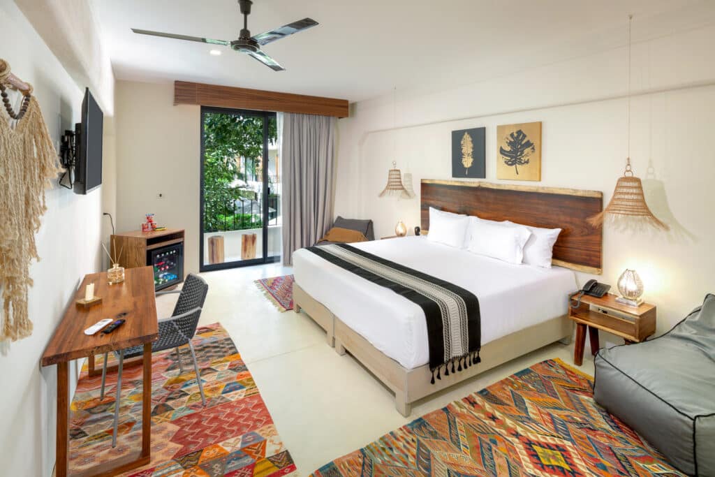 Comfortable hotel room at Tulum 95 Room Hotel in Tulum, with a king-size bed, decorative artwork, and balcony overlooking