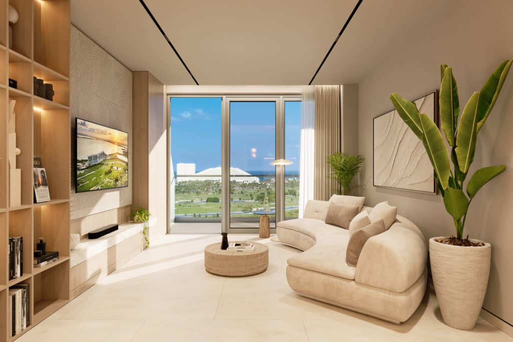 Living room of Bay View Grand 1419-B in Cancun with a beige curved sofa, large potted plant, modern artwork, and a view of Grand Island through floor-to-ceiling windows.