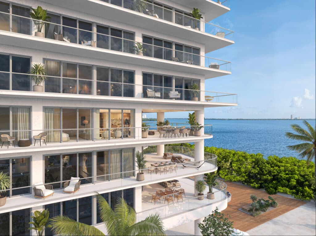 Balcony view of Bay View Grand 1419-B in Cancun's Grand Island, featuring multiple outdoor seating areas with lush plants and overlooking the water and distant city skyline.