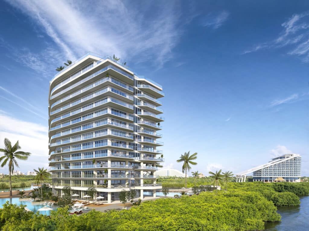 Modern white condominium building with multiple balconies in Bay View Grand 1419, Cancun, surrounded by lush greenery and located on Grand Island.