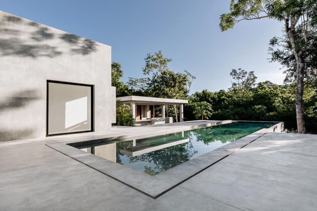 A modern house with a pool surrounded by lush greenery in Rancho Viejo, Tulum, within the Villa Amanai development.