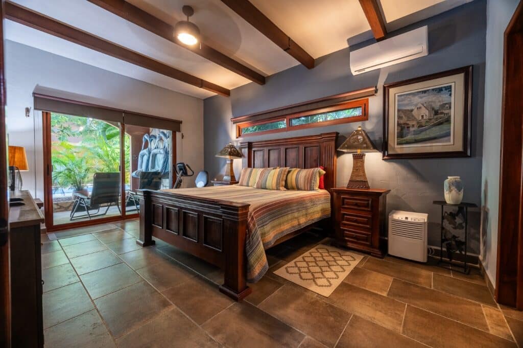 Bedroom with wooden furniture and tiled flooring in Villa Bonita Christies 42 at Casa Bonita, El Cielo, Playa del Carmen, with sliding glass doors leading to an outdoor sitting area.