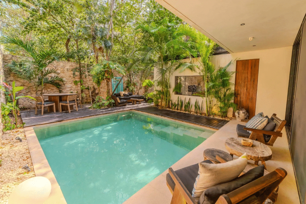 A private pool area surrounded by lush greenery at Villa Kaan, located in Holistika, Tulum, with outdoor seating and a cozy lounge space.
