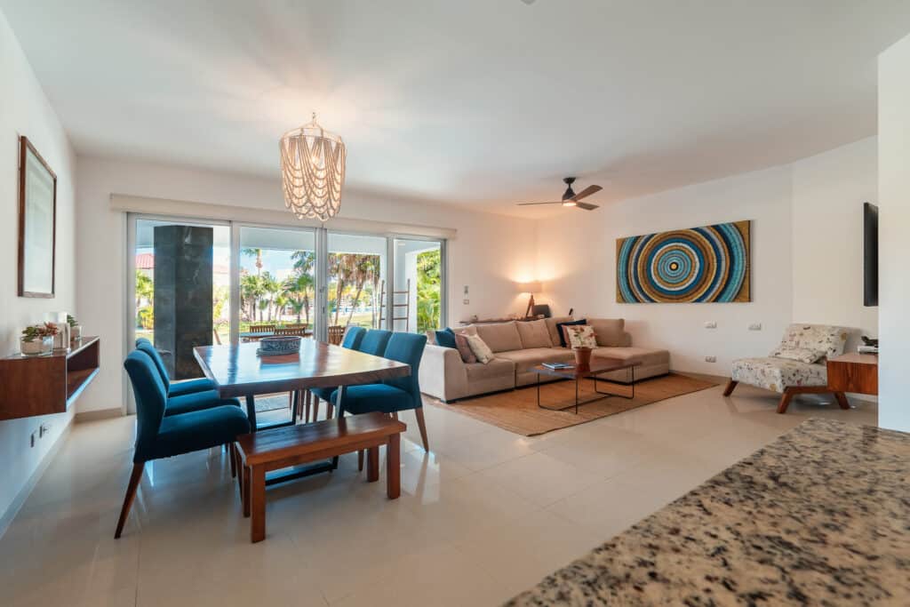 Interior view of Mareazul 401 Sur in Corasol, Playa del Carmen, showing a spacious living and dining area with large glass doors opening to a balcony with tropical views.