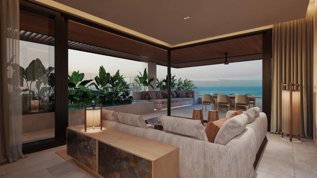 A spacious living area at Belmare 312 features sliding glass doors leading to a balcony with ocean views, lush greenery, comfortable seating, and a modern, elegant design in Tulum.