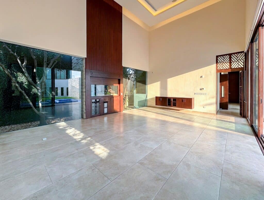 Spacious living area at Bosques De Altabrisa in Merida, featuring large windows, tiled floors, and a modern design with wood accents and natural light.